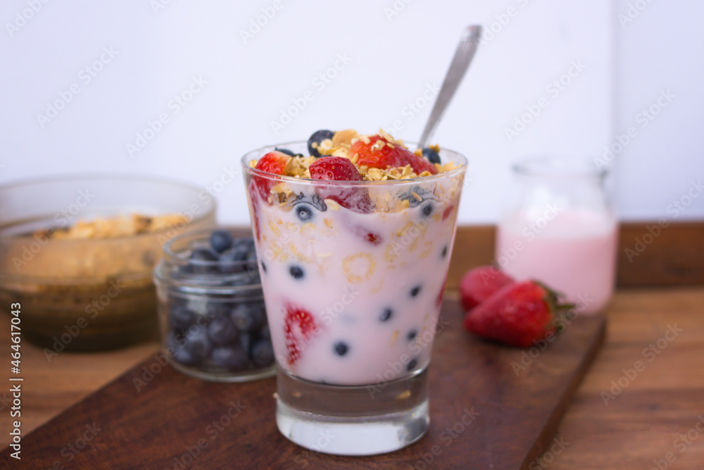 glass with yogurt, cereals, strawberries and blueberries on wooden table glass with yogurt, cereals, strawberries and blueberries on wooden table