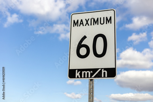 Speed limit road sign against blue sky with clouds