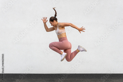 Fototapeta Naklejka Na Ścianę i Meble -  Young fitness girl in training sportswear jump high in jogging exercise outside on street.