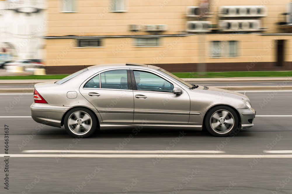 Mercedes-Benz C-Class W203 driving on the street on high speed. Beige  Mercedes C Class sedan in motion, side view Stock Photo