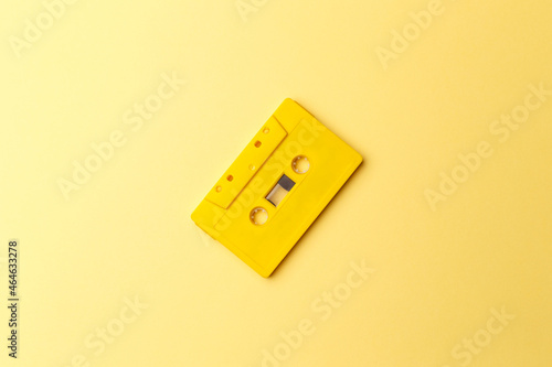 Vintage yellow audio cassette on bright yellow background. Audio cassettes with magnetic tape. Vintage audio recording storage and playback tools. Music concept. Retro