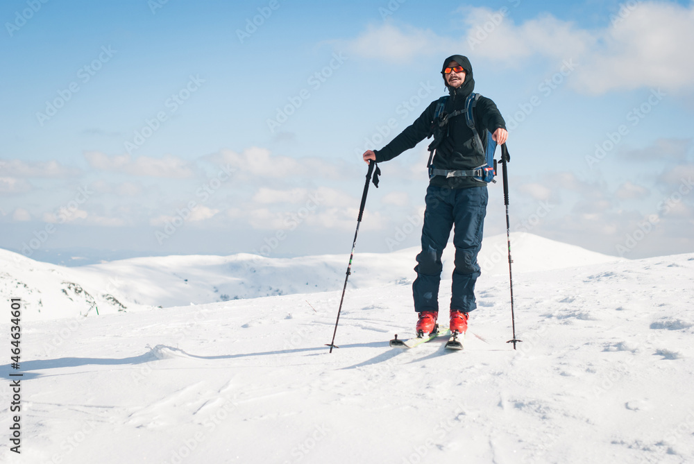 Backcountry skiing in the mountains. A happy young man who reached a summit and is ready to go downhill. Backcountry skiing in the mountains. A happy young man who reached a summit and is ready to go downhill.