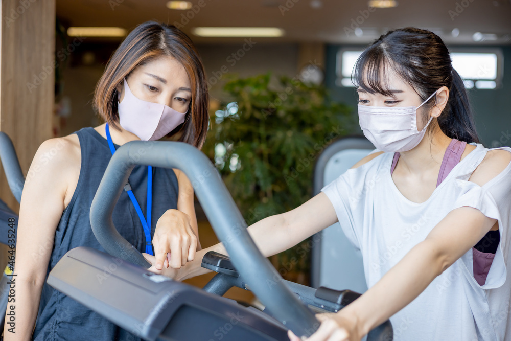 スポーツジムで指導を受ける女性(マスク)
スポーツジムで指導を受ける女性(マスク)