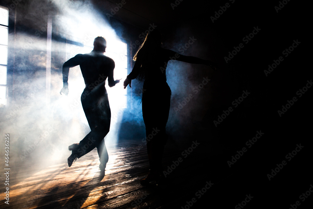 Couple of two professional ballroom dancers is dancing on loft studio. Beautiful art performance with heavy smoke. Sport life concept. Passion and emotional dance.