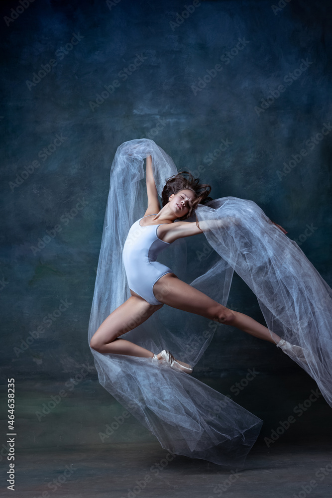 Portrait of young and flexible ballet dancer, ballerina dancing isolated on dark vintage studio background. Art, motion, action concept.