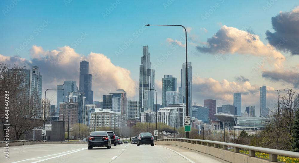 Chicago Illinois, USA. Cars on the road driving to Chicago city, high rise buildings and cloudy sky background