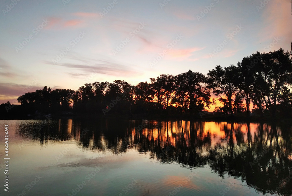 Sunset oner the lake in which the trees are reflected Sunset oner the lake in which the trees are reflected