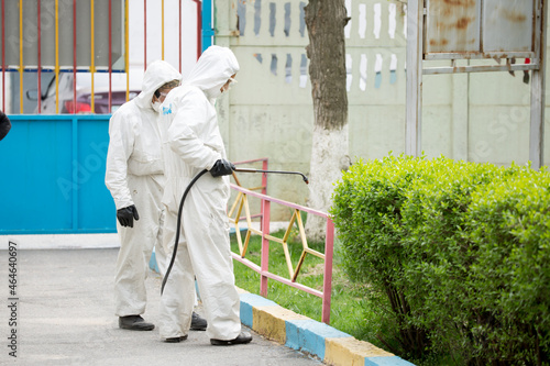 People in protective suits disinfect on the streets of the city. Epidemic corona virus, pandemic worldwide. Disinfection of surfaces from viruses in quarantine. Spraying with disinfectants.