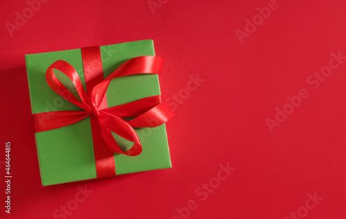 gift box green on red background with red bow with place for text 
