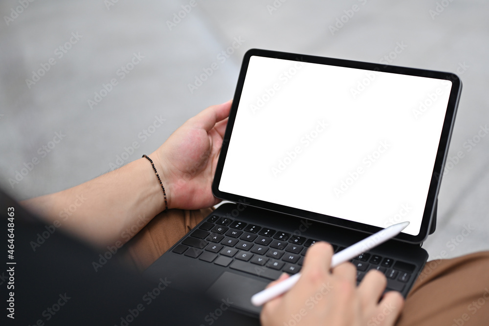 Cropped image of man hand using a white blank screen digital tablet and stylus pen that putting on his lap. Cropped image of man hand using a white blank screen digital tablet and stylus pen that putting on his lap.