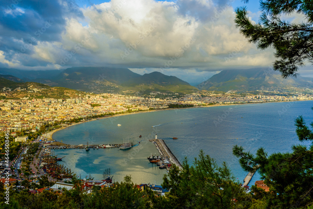 view of Alanya and the port illuminated by the setting sun with colorful clouds in autumn
