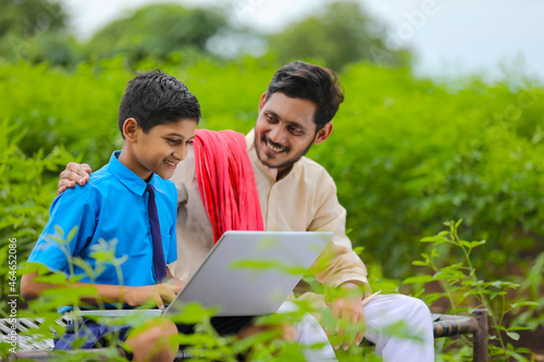 Education concept :cute indian school boy using laptop and giving some information to his father.