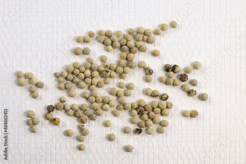 Spices, white peppers, pepper seeds sprinkled on white textured background, close-up
