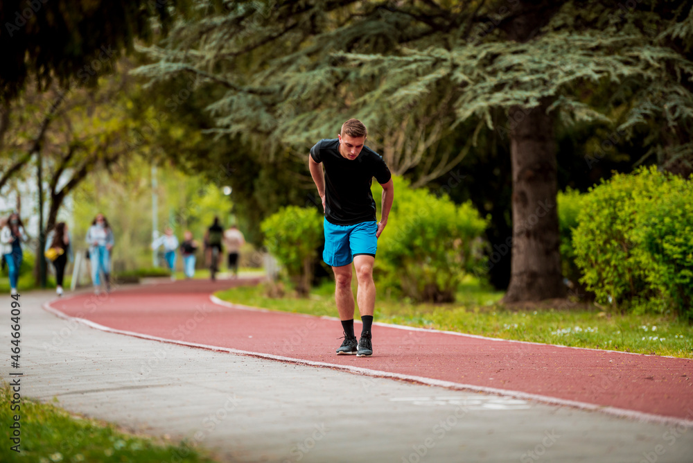 Young guy is jogging on running track in park Young guy is jogging on running track in park
