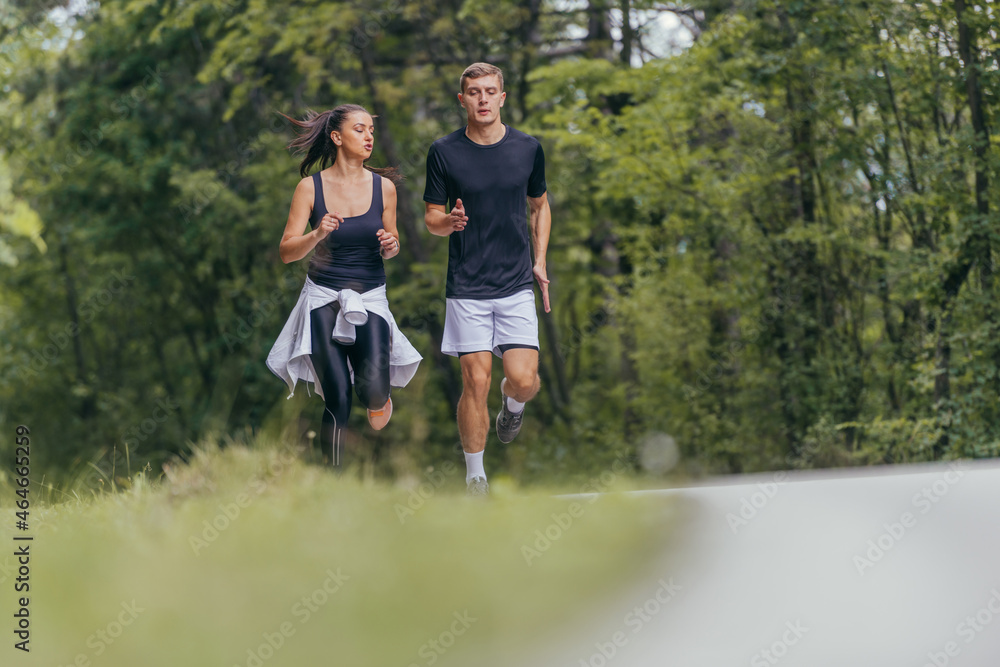 Young fit couple atheltes running on running road in a forest. Young fit couple atheltes running on running road in a forest.