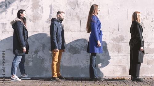 New is normal, health, covid-19, social distance concept. Young people standing near white wall with distance from each other and wearing black medicine protective face masks during pandemic outbreak