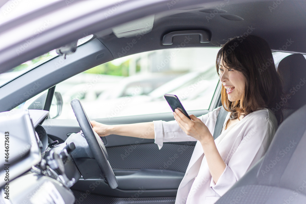 スマホを使いながら車を運転する女性 スマホを使いながら車を運転する女性