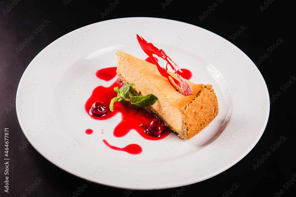Berry cake with decoration on a round white plate on a black background