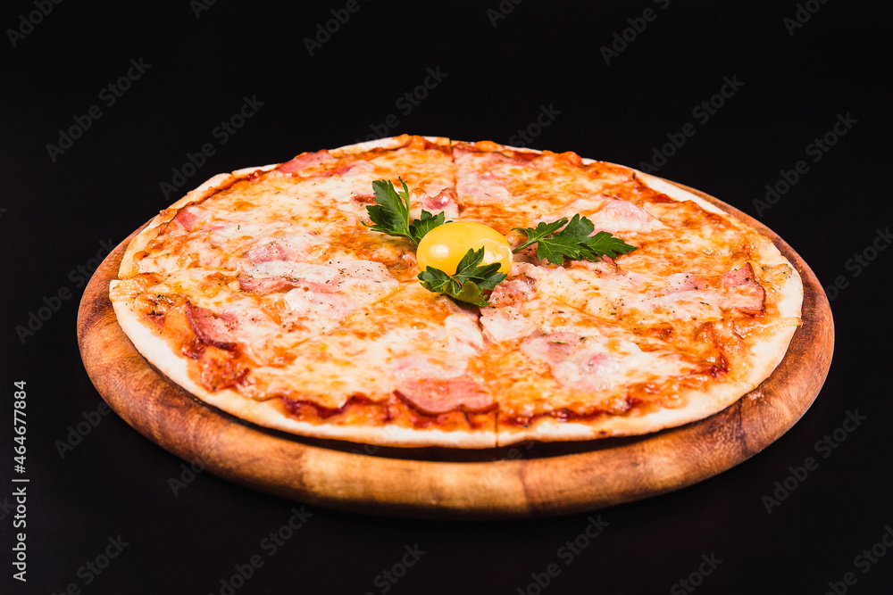 Round pizza with an egg on a wooden board on a black background
