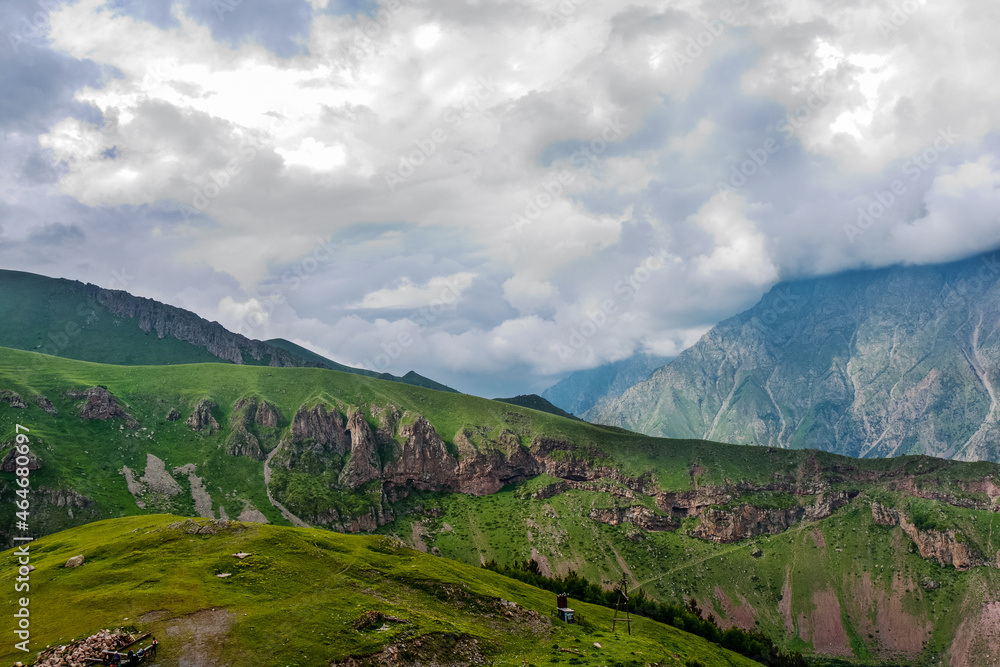 Kazbegi Mountains. View from the mountain to the city, the village of Stepantsminda. Green hills, mountain peaks. Travel in the mountains of Georgia.