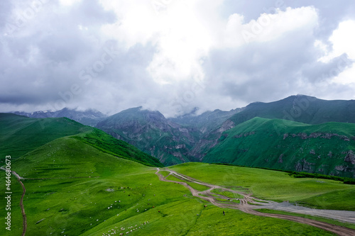 Kazbegi Mountains. View from the mountain to the city, the village of Stepantsminda. Green hills, mountain peaks. Travel in the mountains of Georgia.