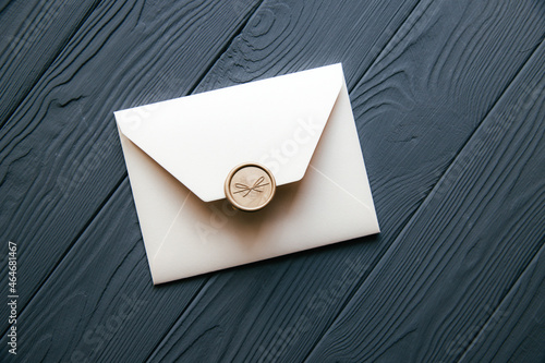 Beige envelope on a dark gray wooden table background. Invitation envelope for wedding, holiday, birthday, party invitation, Christmas envelope. Cose up photo.