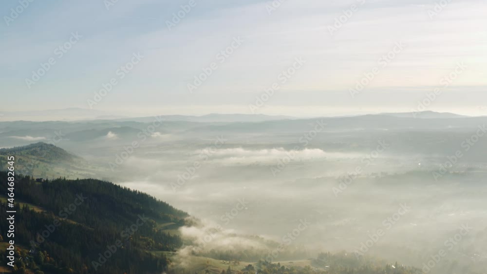 Aerial view flight over amazing hilly landscape lit with warm sunlight. Drone shot hills in haze sunrise light. Beautiful autumn day, village covered with fog. Sunrise, misty morning Aerial view flight over amazing hilly landscape lit with warm sunlight. Drone shot hills in haze sunrise light. Beautiful autumn day, village covered with fog. Sunrise, misty morning