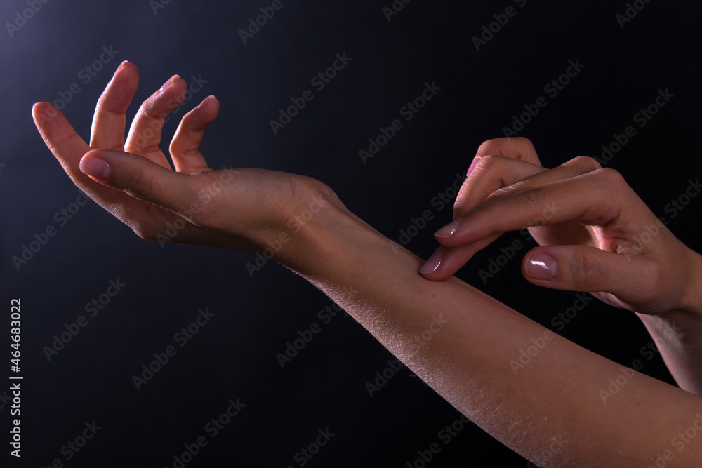 Female hands illuminated by light on dark background