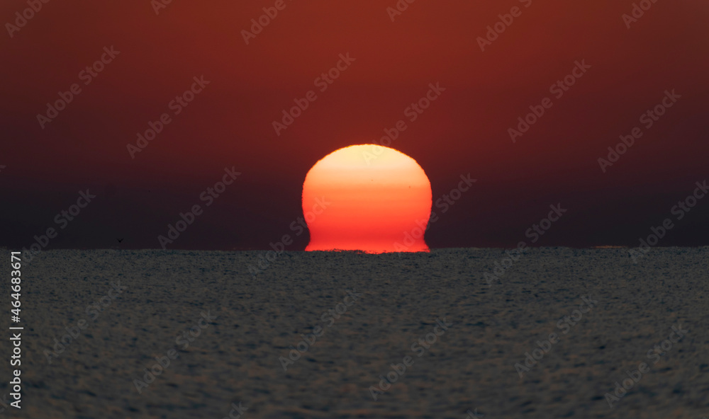 Spectacular sunrise. The sun rises from the sea. Optical illusion.