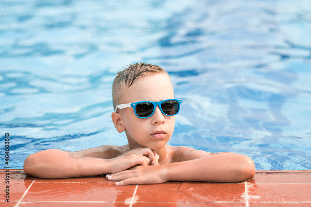 Boy in sunglasses in the pool. Summer vacation of a child in the pool.