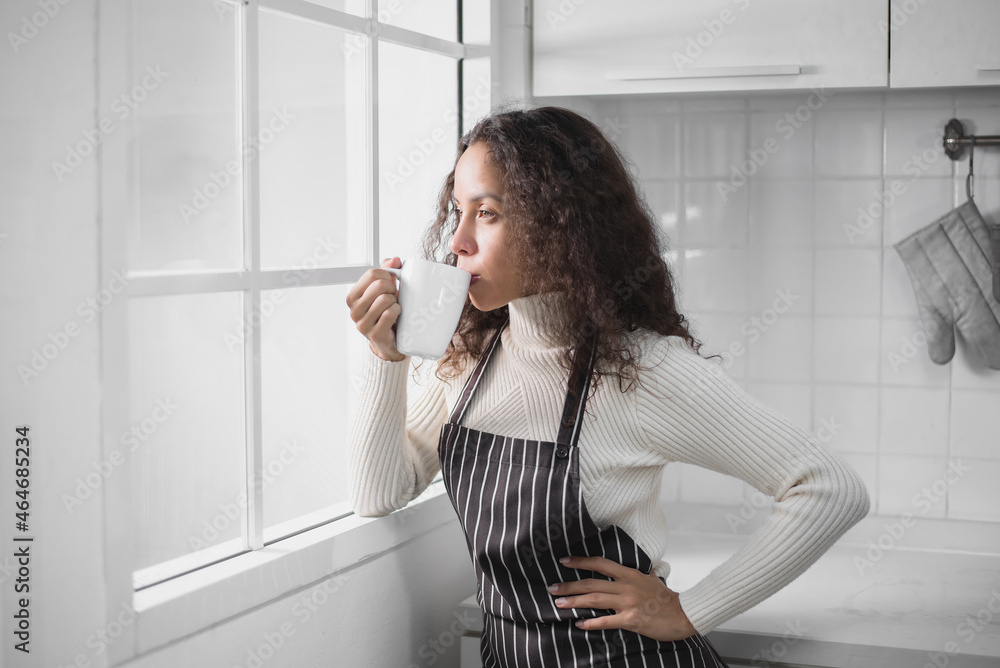 A Latin woman drinking coffee while having breakfast in the kitchen. A Latin woman drinking coffee while having breakfast in the kitchen.