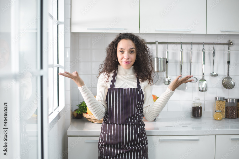 Portrait of a Latin woman smiling happily and showing various gestures in the kitchen.