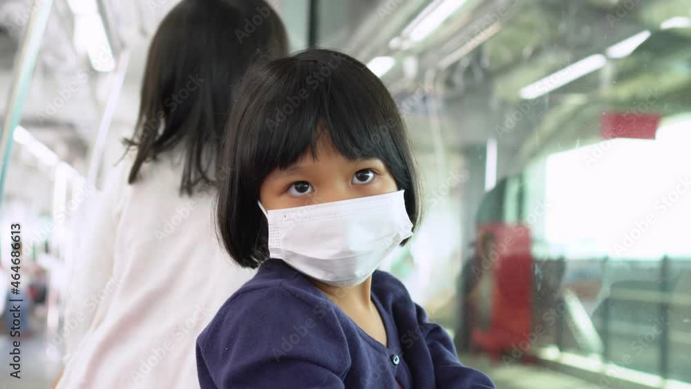 Little girl with surgical mask face protection flu and Virus outbreak in public transportation (skytrain or subway). Concept of New normal lifestyle, Using public transport to travel to school. Little girl with surgical mask face protection flu and Virus outbreak in public transportation (skytrain or subway). Concept of New normal lifestyle, Using public transport to travel to school.