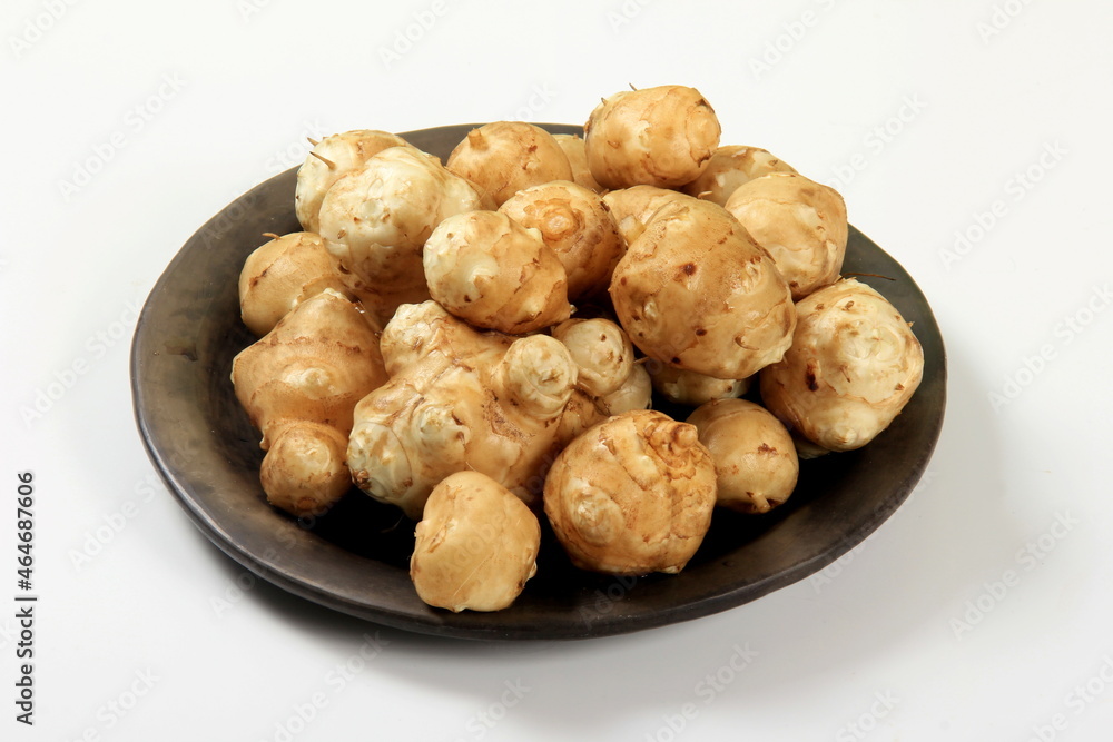 Raw Organic Jerusalem Artichoke in a black clay plate, isolated on white Raw Organic Jerusalem Artichoke in a black clay plate, isolated on white
