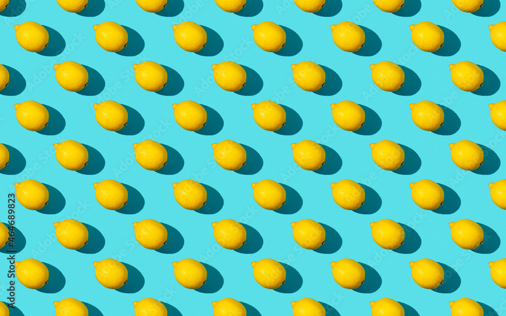Trendy sunlight summer pattern made with yellow lemon slice on bright light blue background. Minimal summer concept. Flat lay.