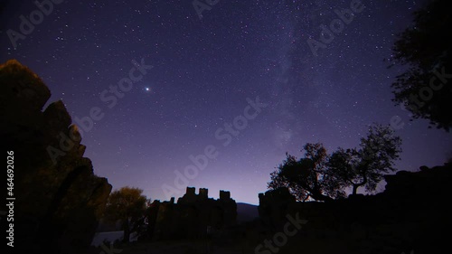 old castle in the night. Timelapse of moving star trails in night sky. A view of the stars of the Milky Way with a mountain top in the foreground. Perseid Meteor Shower observation. photo