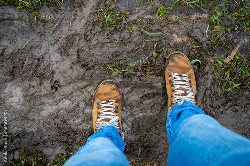 Top view photo of engineering man wearing jeans and brown leather shoes standing on muddy ground after heavy rain