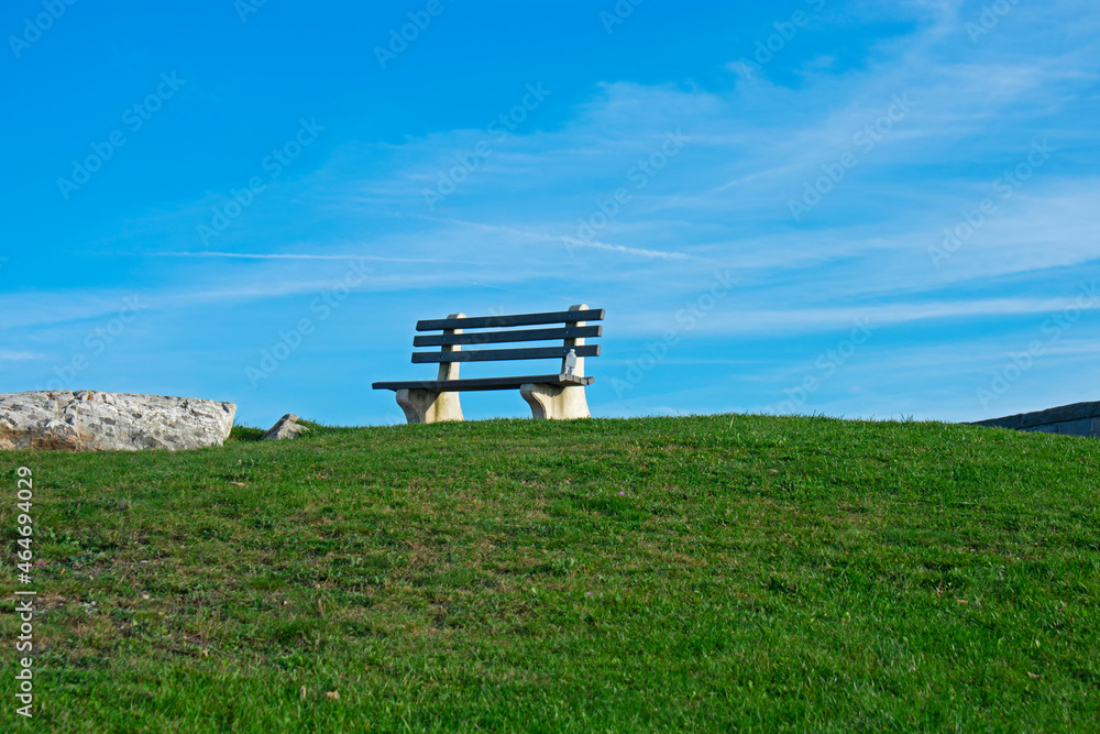 Isolated wooden bench on a grassy hill on a sunny autumn day -11