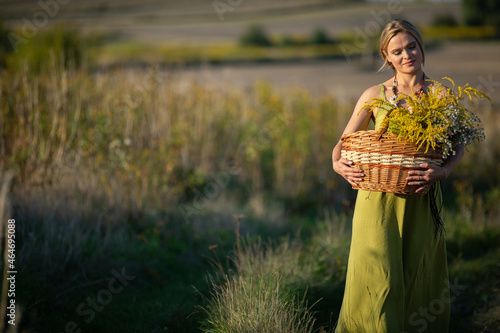 Foto A young attractive herbalist holds a wicker basket of herbs