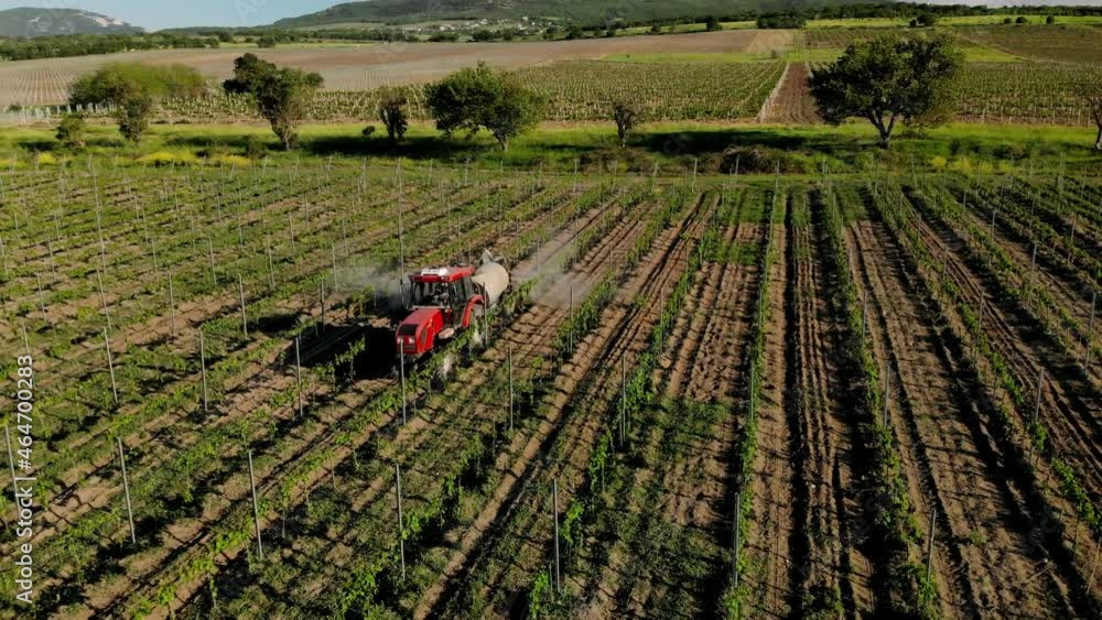 Aerial view of farming tractor spraying on field with sprayer, herbicides and pesticides at sunset. Farm machinery spraying insecticide to the green field, agricultural natural seasonal spring works. Aerial view of farming tractor spraying on field with sprayer, herbicides and pesticides at sunset. Farm machinery spraying insecticide to the green field, agricultural natural seasonal spring works.