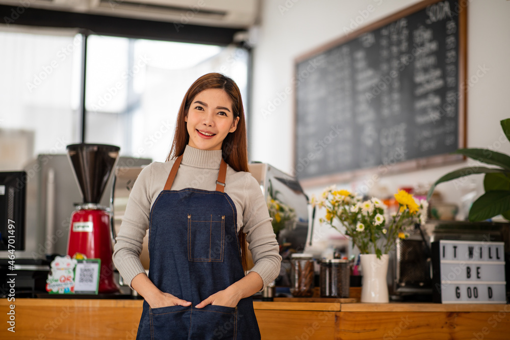 Portrait of a happy young asian Small business owner at entrance looking at camera near a counter in her cafe.