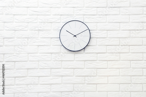 Round clock on white brick wall background