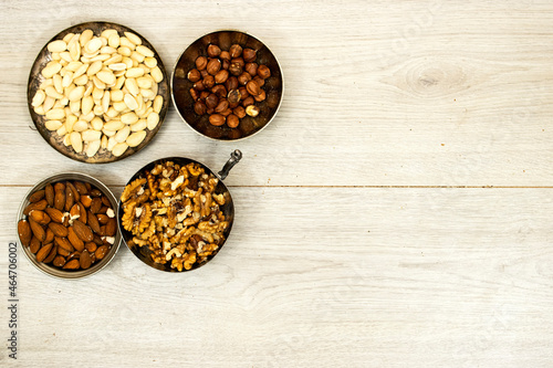 Assortment of nuts in metal bowls hazelnuts, walnuts, almonds on wood table
