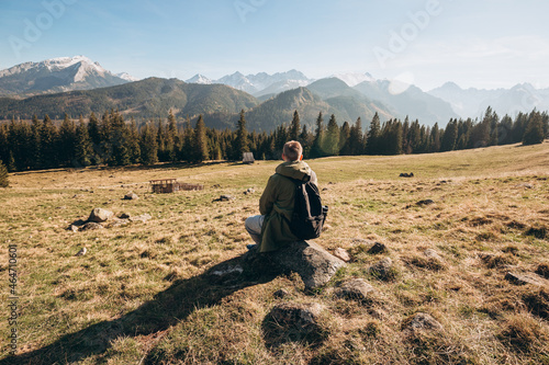 Young man in sunglasses with backpack see view on top mountain. Freedom  happiness  travel and vacations concept  outdoor activities. Man standing backwards looking away