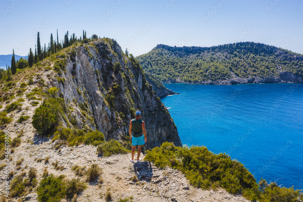 Aerial photo of man traveler on the cliff edge of beautiful and picturesque rocky coast close to Assos village on Cefalonia Ionian island, Greece