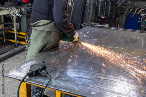 Bright sparks fly over the work table when grinding metal