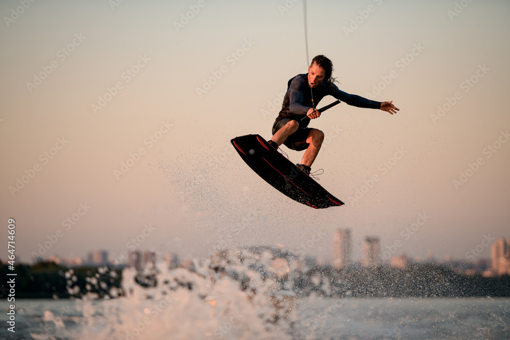 gorgeous view of male wakeboarder while jumping in the air on wakeboard