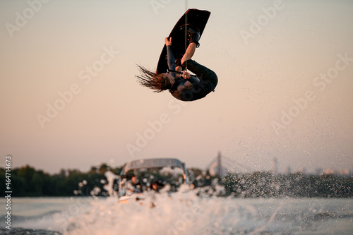 male wakeboarder makes extreme stunts jumping and flips on wakeboard over splashing wave