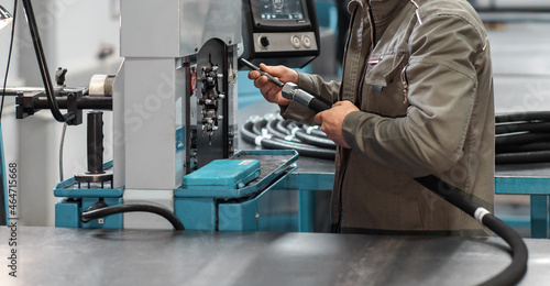 A worker crimps a high pressure hydraulic hose on the machine. High pressure hydraulic hose manufacturing process. photo