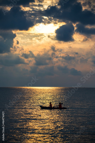 Silhouette two women kayaking boat on sea at sunset with light reflection on water and many cloud. Sport and recreation actvity during holiday vacation at summer in tropical country. photo